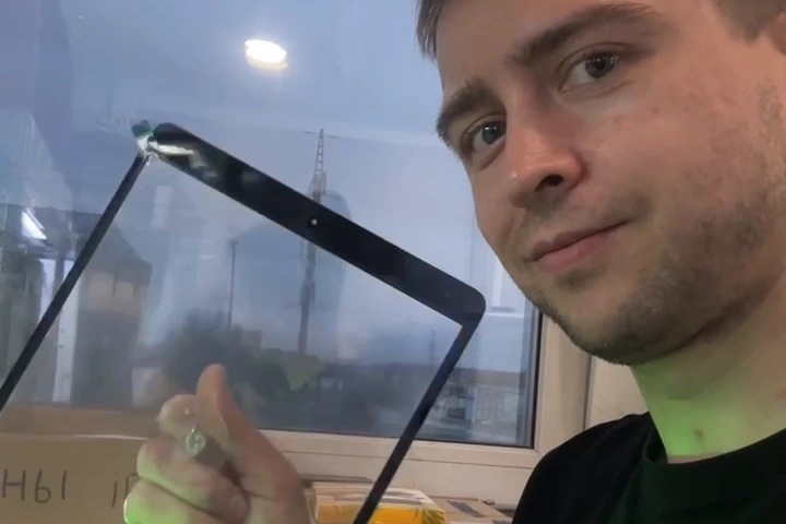 Кадр из видео: мастер показывает стекло iPad в процессе ремонта